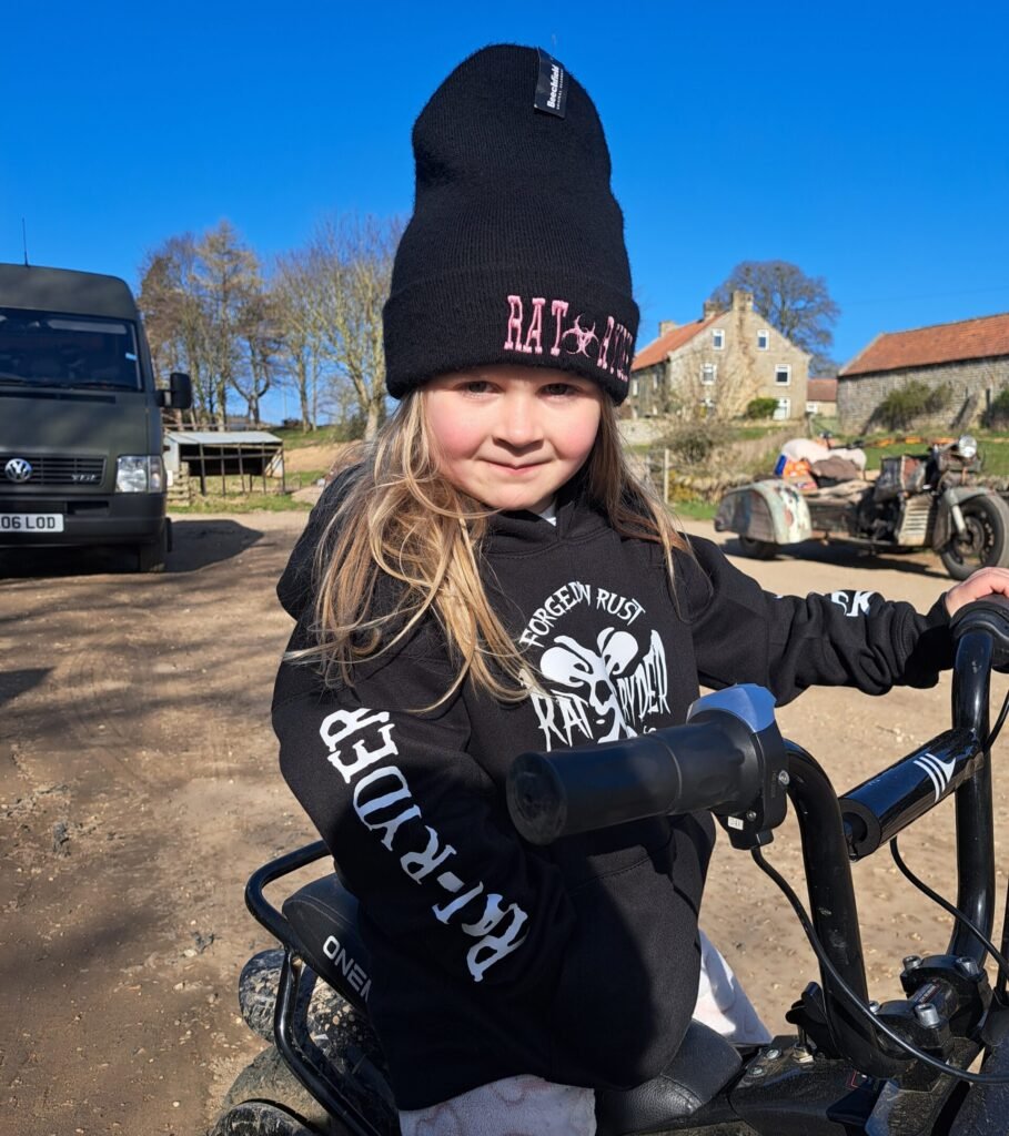 Close-up of child in Rat-Ryder Forged in Rust hoodie on a dirt bike outdoors