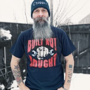 Man wearing a black 'Built Not Bought' T-shirt with bold red and white graphic, standing outdoors in a snowy background