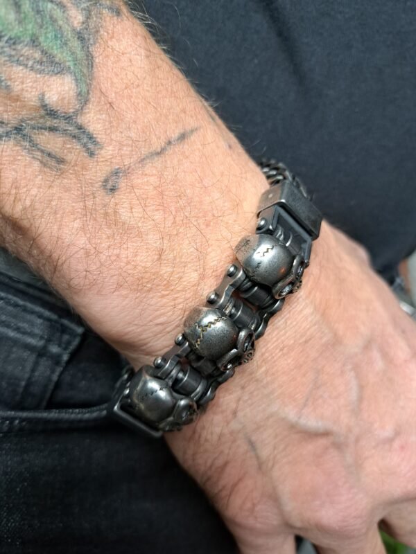 Side view of the 225mm stainless steel biker bracelet featuring oxidized skull heads and interlocking chain links.