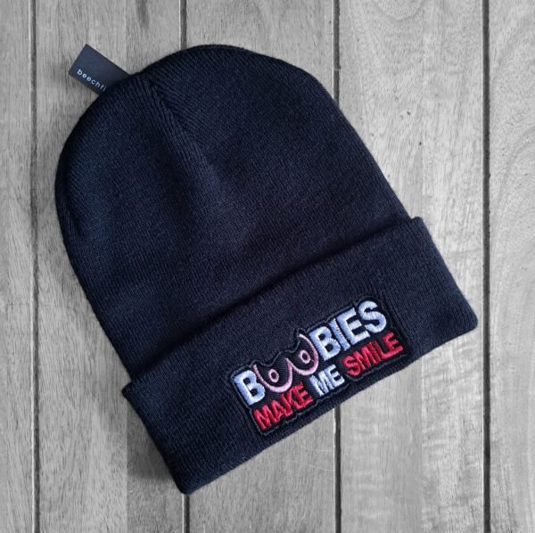 Black beanie with embroidered slogan 'Boobies Make Me Smile' in pink, white, and red thread.