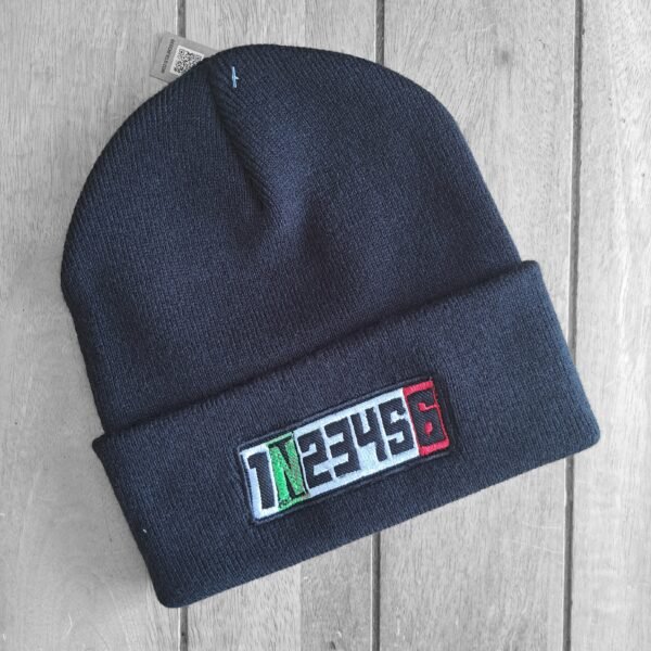 Black motorcycle beanie with embroidered 1N23456 gear shift design in green, white, and red, displayed at an angle on wooden background.