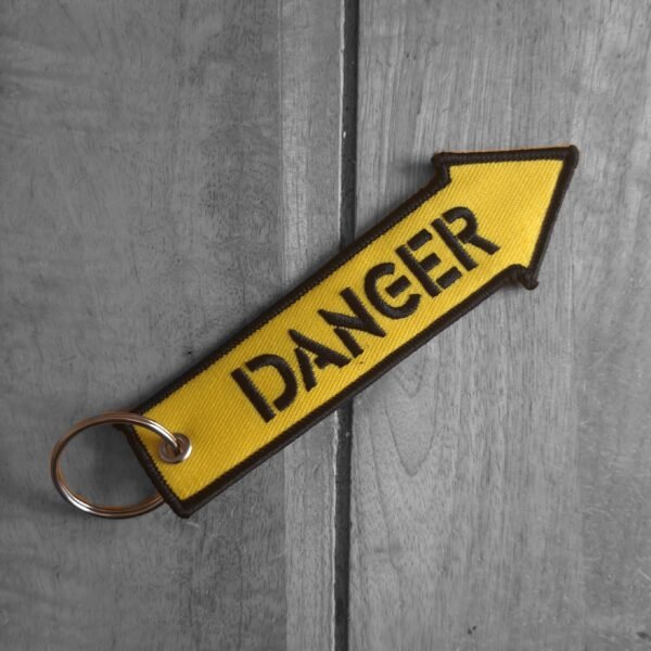 Yellow embroidered DANGER arrow keytag on wood