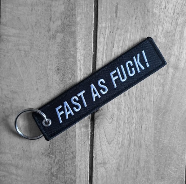 Angled Fast As F*ck biker keytag on wooden surface