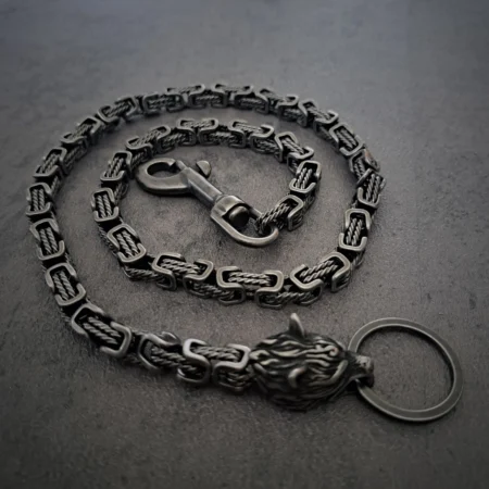 Rat-Ryder heavy stainless steel biker wallet chain with a wolf head Byzantine biker wallet chain laid out in a spiral on a dark slate background.