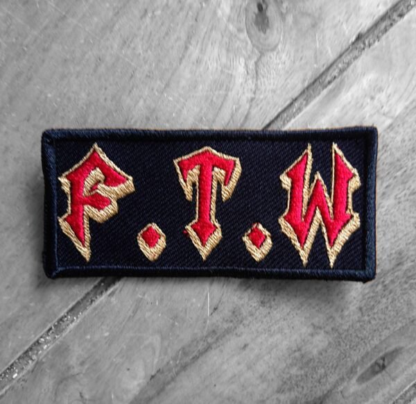 Embroidered F.T.W. patch with red Gothic-style lettering outlined in gold on a black background.