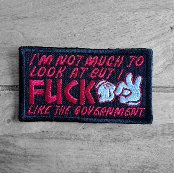 Front view of embroidered patch with edgy political text and cartoon-style hands replacing letters.