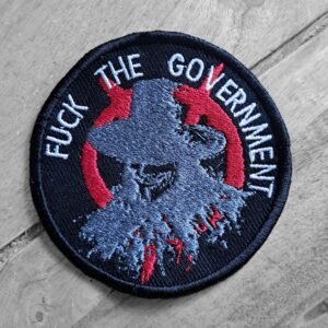 Round embroidered patch with stylized Guy Fawkes design and the words "Fuck the Government" in white thread, angled view.