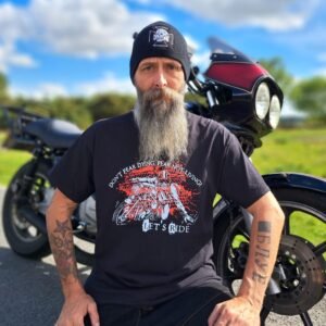 Black t-shirt with “Don’t Fear Dying, Fear Not Living! Let’s Ride” motorcycle graphic, lifestyle shot beside a bike.