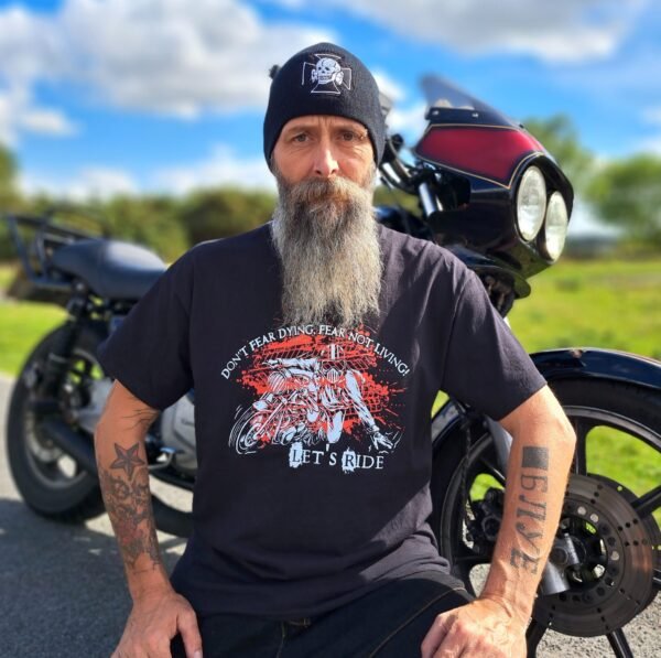 Black t-shirt with “Don’t Fear Dying, Fear Not Living! Let’s Ride” motorcycle graphic, lifestyle shot beside a bike.