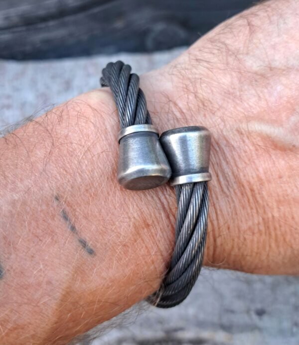 Stainless steel braided cable cuff on a wrist; 9mm cable with 13mm end caps; biker/Norse style.