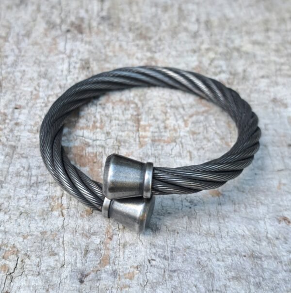 Angled close-up of braided stainless wire-rope bracelet; 9mm cable with 13mm end caps.