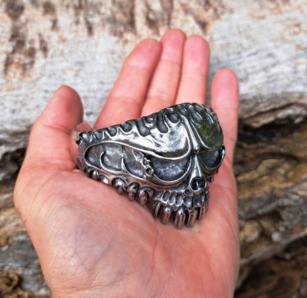 Stainless steel skull bangle bracelet held in hand to show size, biker and gothic heavy metal style, 69mm diameter.