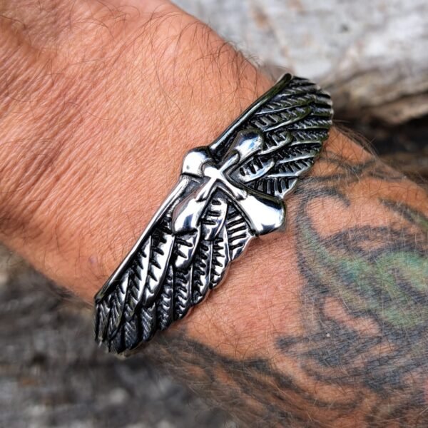 Stainless steel winged cross bangle worn on wrist with tattoo, gothic biker jewelry