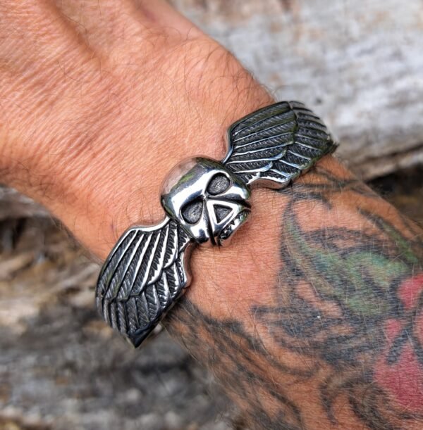 Stainless steel winged skull bangle worn on wrist, biker rock metal jewelry