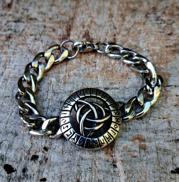 Viking Triquetra bracelet in stainless steel with runes on wooden background