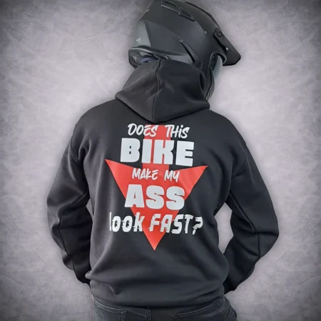 Rear view of a person wearing a black funny biker hoodie featuring a red arrow graphic and the text 'Does this bike make my ass look fast?' while wearing a black motorcycle helmet.