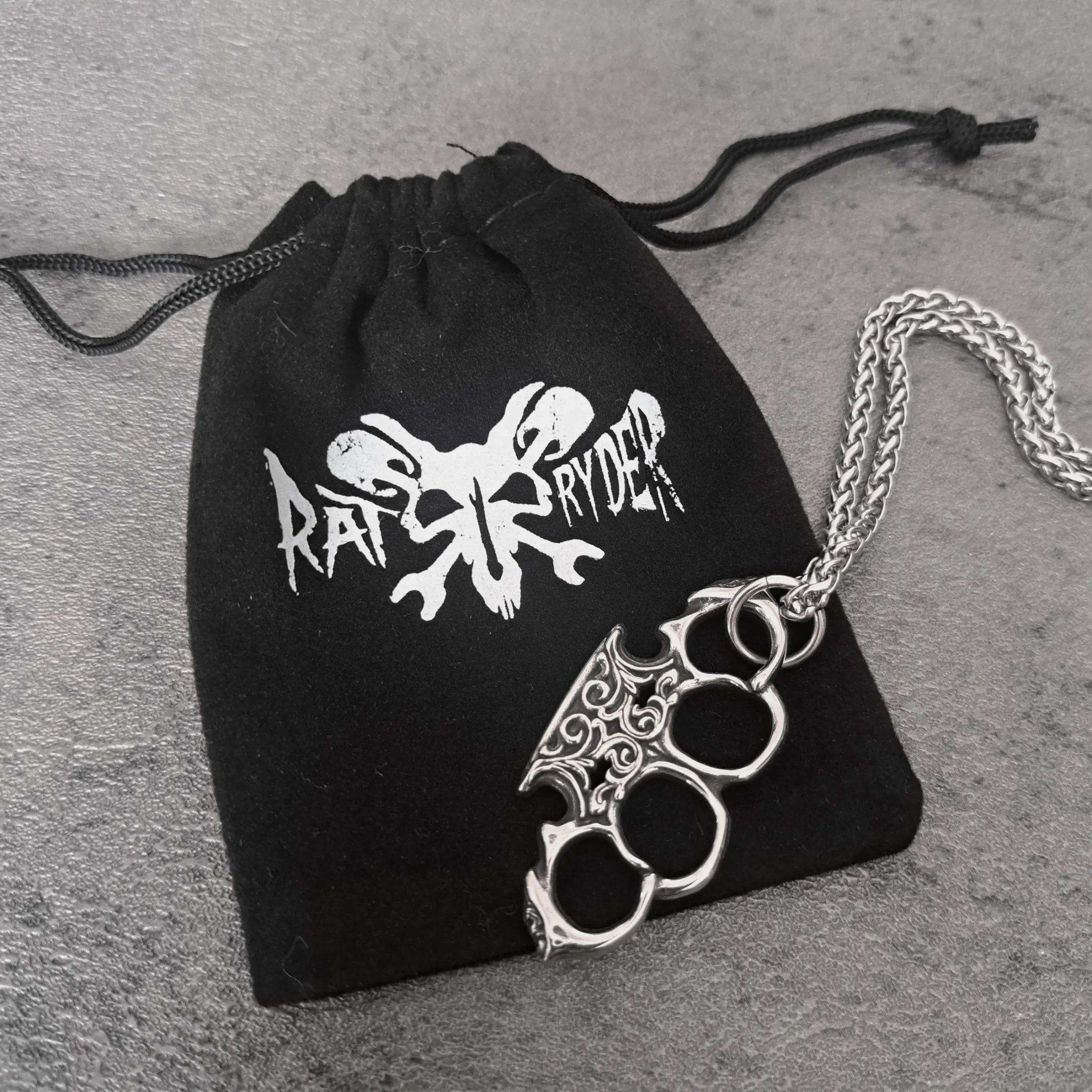 Filigree Knuckle Duster – 316L Stainless Steel Biker Pendant | RatRyder 3 Filigree knuckle duster biker pendant resting on black RatRyder velvet gift bag