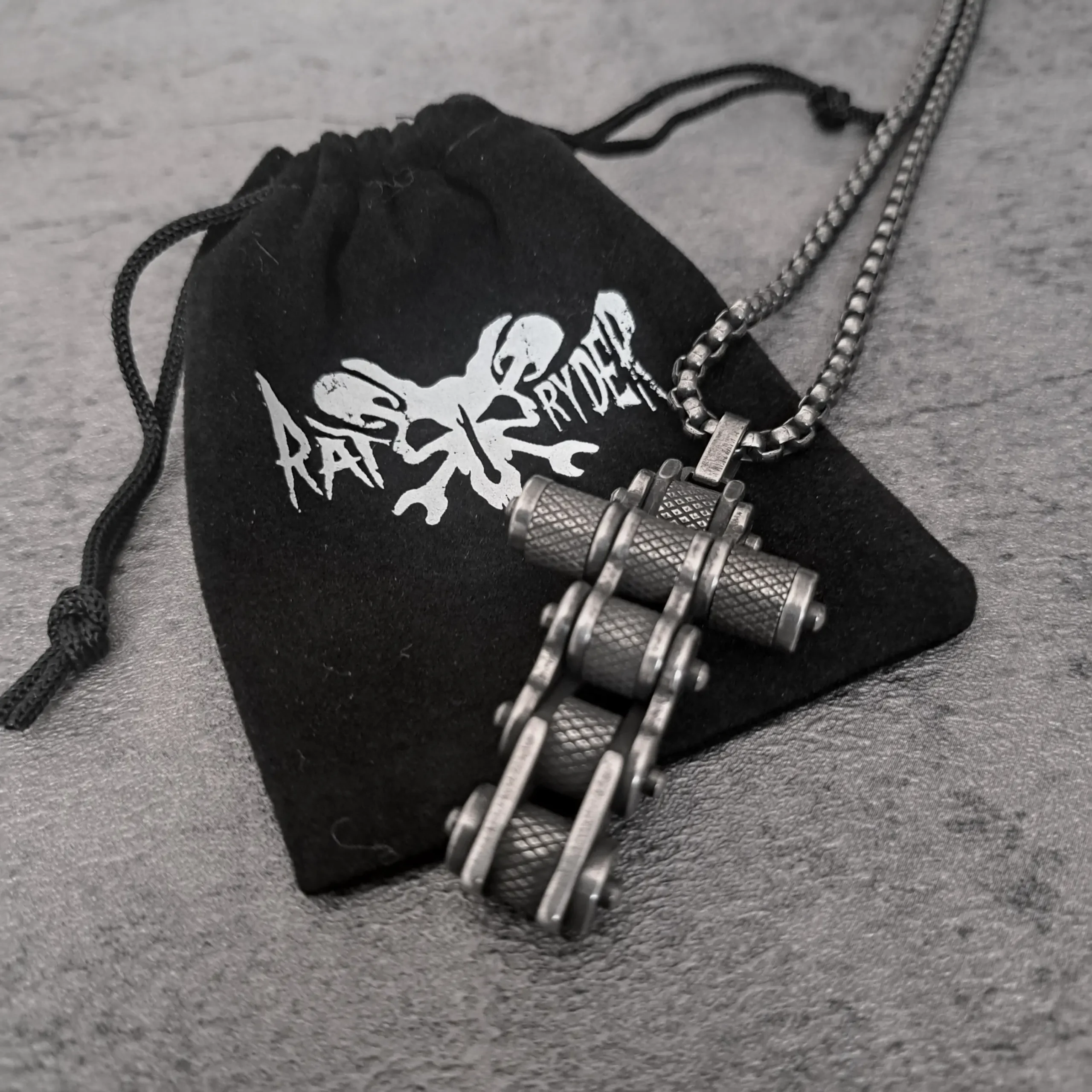 Motorcycle Chain Cross – 316L Stainless Steel Biker Pendant | RatRyder 3 Motorcycle chain cross biker pendant resting on black RatRyder velvet gift bag