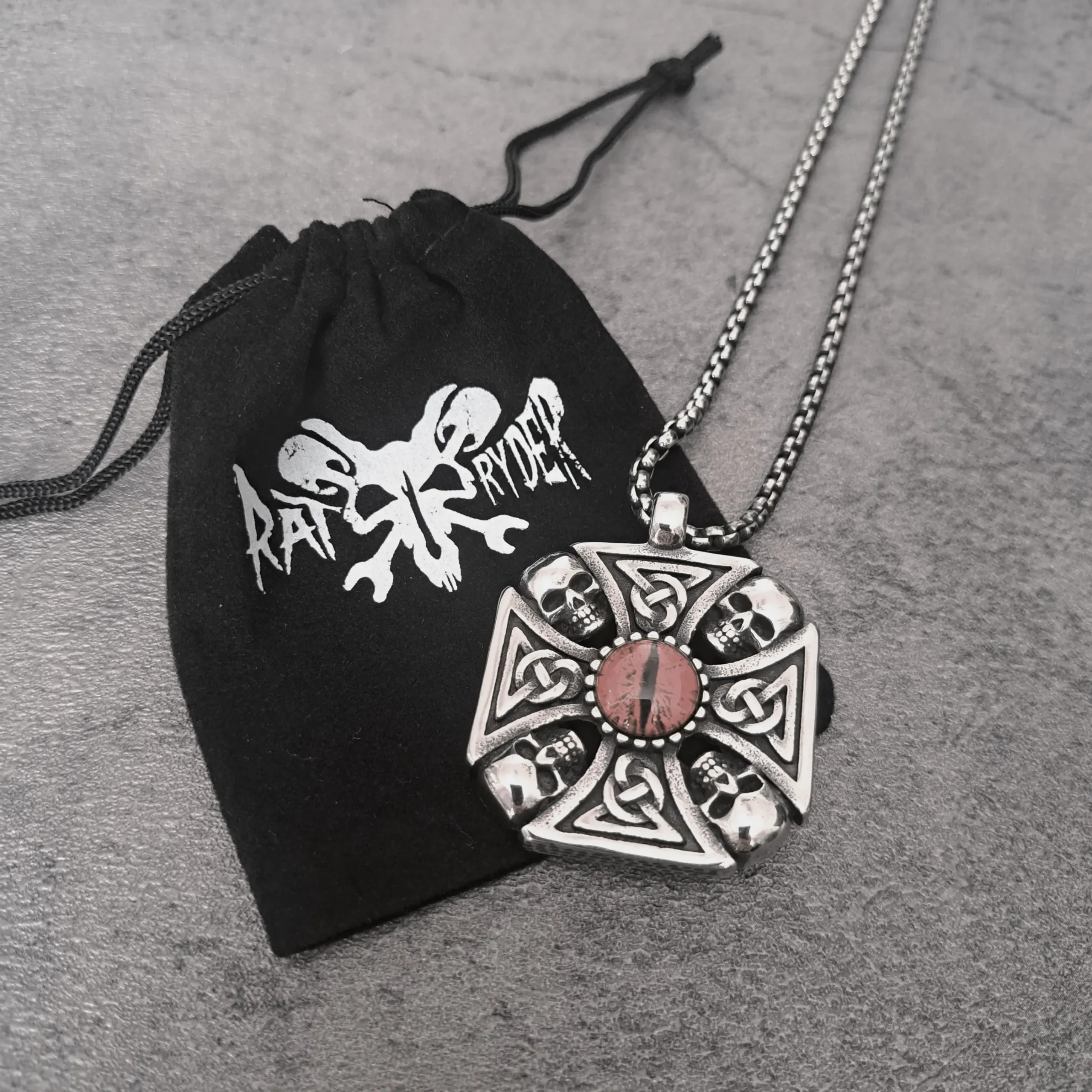 Red Dragon Eye Skull Celtic Cross – 316L Stainless Steel Biker Pendant | RatRyder 3 Red dragon eye skull Celtic cross biker pendant resting on black RatRyder velvet gift bag