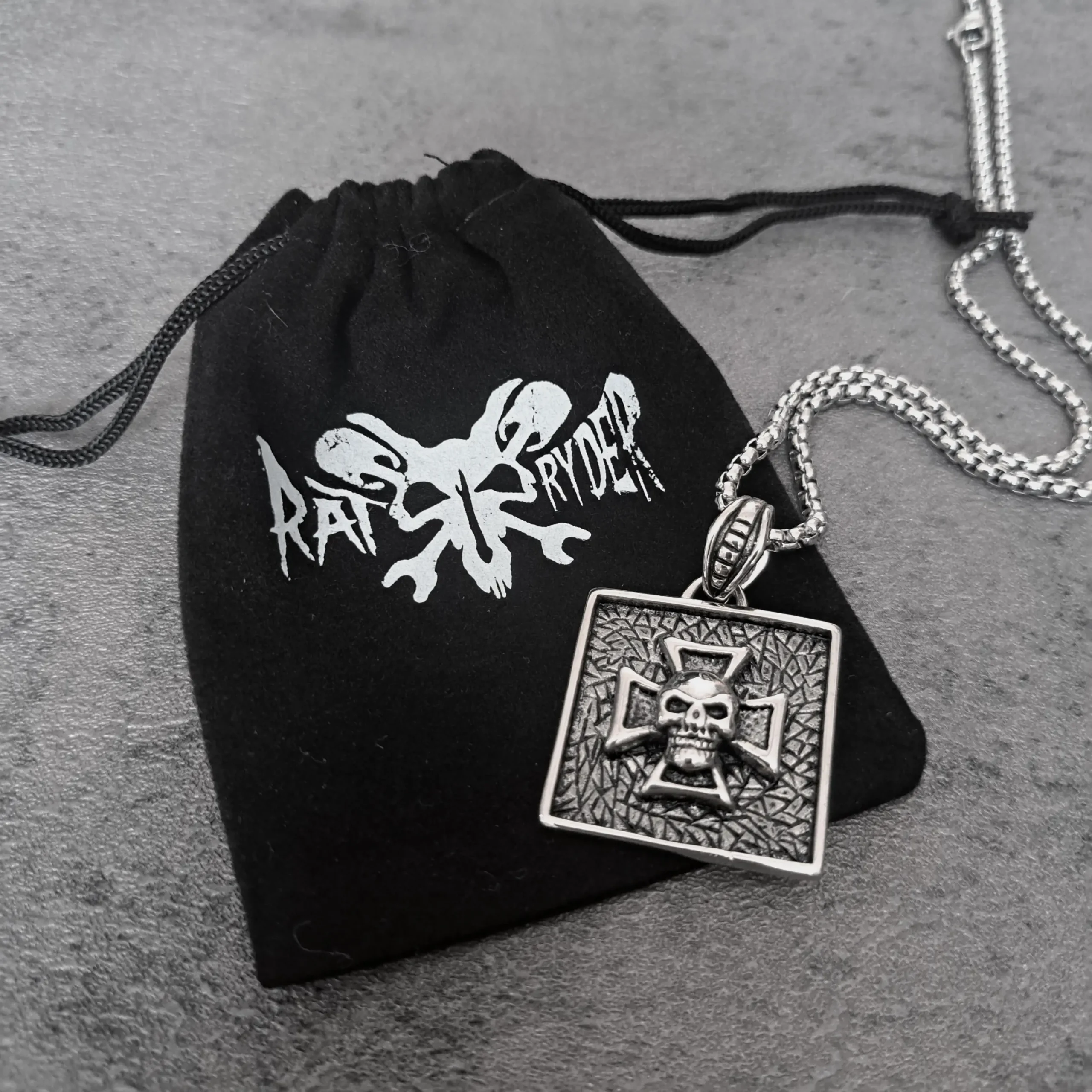 Square Iron Cross Skull – 316L Stainless Steel Biker Pendant | RatRyder 3 Square Iron Cross skull biker pendant resting on black RatRyder velvet gift bag